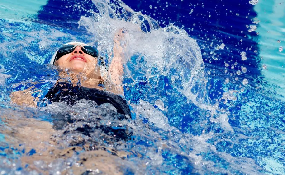 Swimmer performing backstroke with one arm raised out of the water