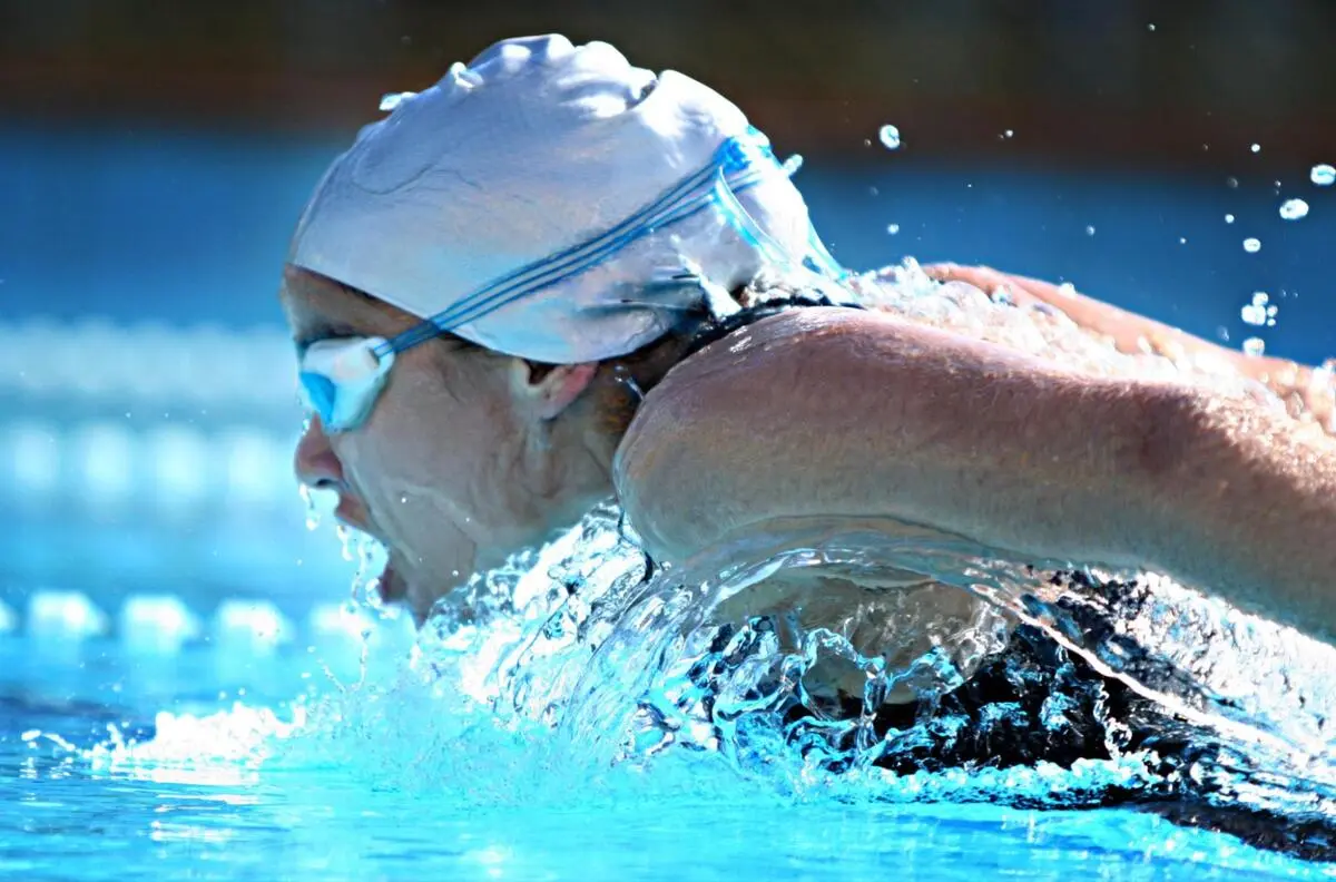 Close-up of a swimmer wearing goggles and cap mid-stroke during freestyle swimming